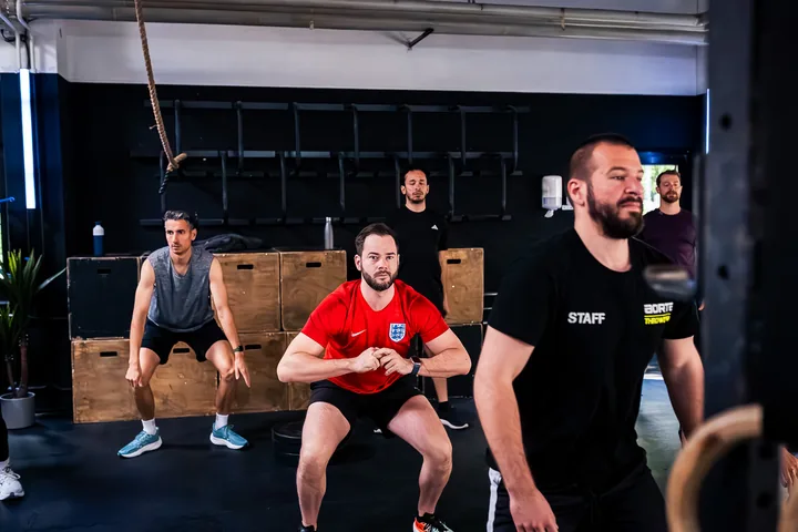 CrossFit-Coach zeigt Anfängern die richtige Squat-Technik bei CrossFit Aorta Berlin